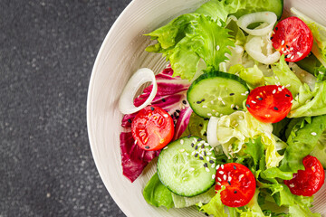 Vegetable salad tomato, cucumber, lettuce, green leaf lettuce, onion appetizer vegetable dish fresh gourmet food background rustic food top view copy space keto and paleo diet vegetarian vegan food