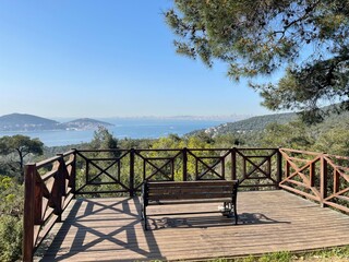 Empty wooden bench on a viewing platform overlooking the sea and city skyline, a concept of peace and quiet for travel and vacation