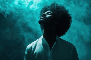 A young man with an afro is looking upward with eyes closed, expressing contemplation. Soft smoke is diffused in background, highlighting his pensive mood