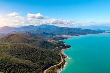 Aerial view Bright blue waters meet lush green hills. Visitors can enjoy the scenic views windy road as they explore the coastline, revealing nature's tranquility and adventure. © aapsky