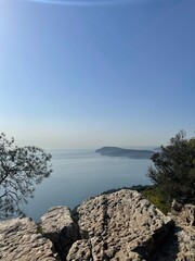 Scenic vista overlooking the ocean from a lush green hill on a bright sunny day with a clear blue sky, perfect for a travel brochure