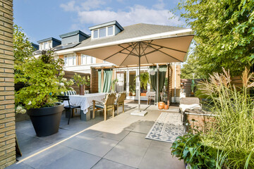 A beautifully arranged outdoor patio featuring comfortable seating, a large umbrella, and lush...