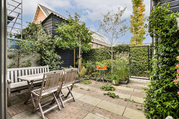 A tranquil garden featuring lush greenery, a wooden table and chairs, and beautiful plants. Perfect for relaxation or outdoor dining.
