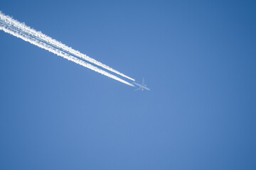 jet liner aircraft in deep blue sky, contrails vapour trails