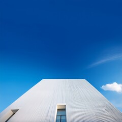 シンプルで直線的な白い四角い建物が、広大な青空を背景に立つ風景。開放感があり、コピースペースを活かした清潔感のあるシーン。

