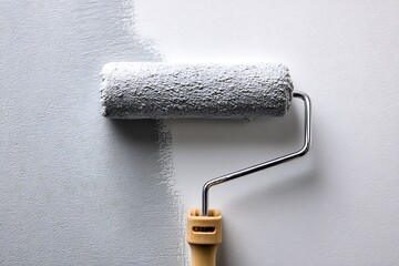 Obraz premium Gray paint applied by roller close-up symbolizing home renovation projects 