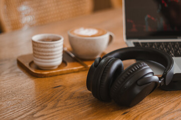 Business workspace for entertainment media with laptop, headphones and coffee cup on morning desk