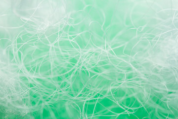 Extreme macro of polyester stable fiber on green background. Selective focus, shallow depth of field. Abstract dreamy background