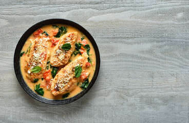 Chicken breast in creamy sauce with tomatoes and spinach in pan