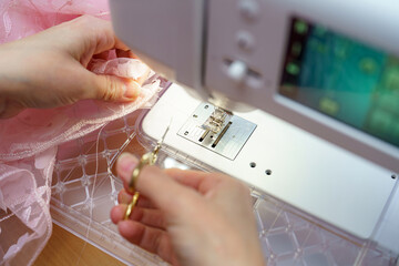 Sewing delicate lace fabric with precision at a crafting table in a bright workshop during the daytime