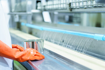 QC officer inspecting a canned food on production belt.