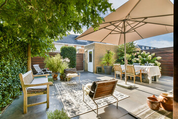 A beautifully designed outdoor patio featuring lush greenery, comfortable seating, and an inviting dining setup under a stylish umbrella.