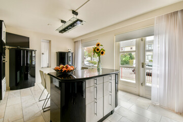 A sleek, modern kitchen featuring black cabinetry, a stylish island, and vibrant sunflowers as a centerpiece near a large window.