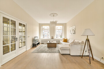 A stylish and serene living room featuring a cozy white sofa, elegant furnishings, and natural light. The minimalist design promotes a calming atmosphere.