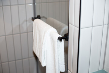 Fresh, clean white towels hanging neatly on a modern towel rack, creating a cozy and inviting...