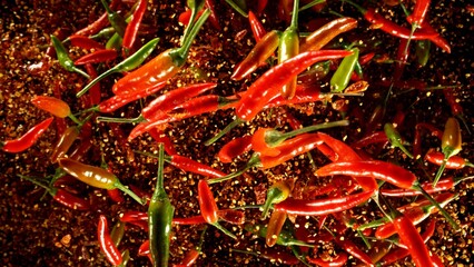 Freeze motion of flying chilli peppers on black background.
