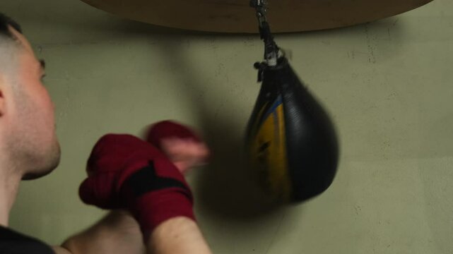 Man throws punches at specially item working out in boxing gym. Sportsman practices professional skills and abilities warming up arm muscles