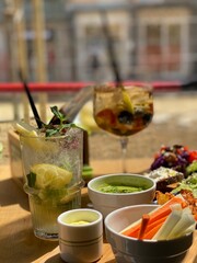 Refreshing cocktails, fresh vegetables and dips served on a wooden table during an outdoor aperitivo in Pescara, Italy