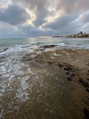 Soft waves washing rocky coastline during golden sunset, tranquil beach scene in Santa Croce Camerina, Sicily, Italy