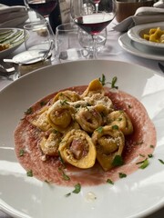Plate of cappelletti with pink sauce, grated cheese and parsley served in a restaurant in Gradara, Italy