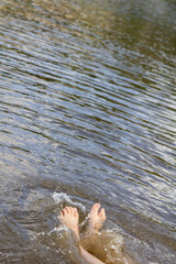 Bare feet of a child splashing and playing in shallow water, capturing a joyful summer moment.
