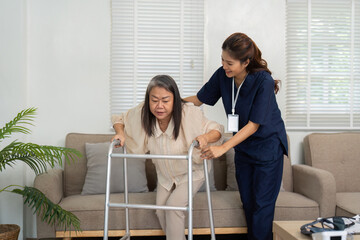 Mobility Assistance and Support. A caregiver helps an elderly woman stand using a walker in a...