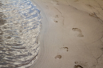Human footprints on sandy ground near the calm edge of the Sozh River, adding a human presence to a quiet natural scene.