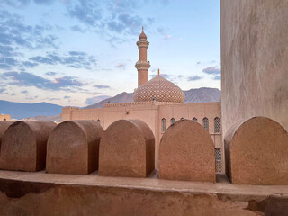 Ancient Nizwa Fort in Oman with traditional Islamic architecture, rounded domes and minaret tower...
