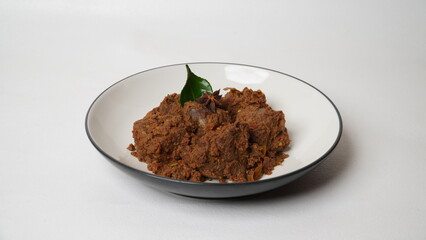 Traditional Indonesian rendang beef dish served on white plate isolated on white background