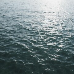 Obraz premium Ocean's Embrace: The vast expanse of the ocean unfurls, a mesmerizing tapestry of gently rippling waves glistening under a soft light, offering a sense of tranquility and awe.