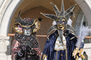 Obraz premium Venice, Italy - People dressed in carnival masks are photographed by tourists in the scenery of the ancient Venetian palaces