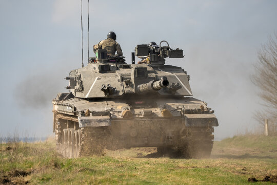 close-up of a commander directing a Challenger 2 II FV4034 main battle tank, reversing away at high speed
