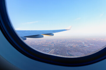 Sunset view from airplane window, airplane wing and earth as seen through window at cloudy sky.