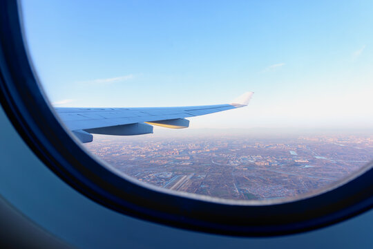 Fototapeta Sunset view from airplane window, airplane wing and earth as seen through window at cloudy sky.