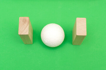 Still life with wooden blocks and a a plastic foam ball on green background	