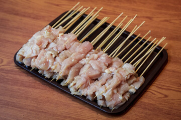 Raw chicken skewers neatly arranged on a tray, ready for grilling. Ideal for barbecue, cooking, or culinary preparation themes. Chicken satay. Selective focus