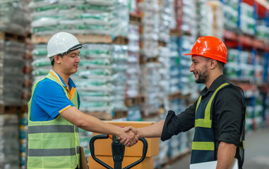 caucasian worker shake hand asian employee at warehouse. shipping stock employee group showing respect with hand shake. logistic team with asian and caucasian guy celebrate congratulation shake hand