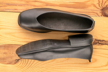 Women's black shoes on a wooden table, close-up, top view.