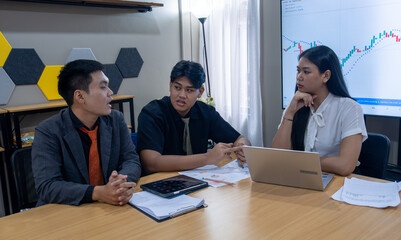 Fototapeta premium Business discussion among three professionals in a modern office setting focused on financial trends and strategies