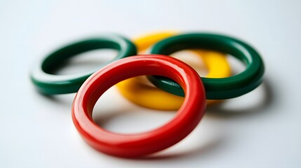 Fototapeta premium Close-up of three vibrant, interlocking plastic rings in red, green, and yellow. The rings are smooth and glossy, creating a colorful and playful image.