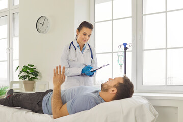 Obraz premium Sick man patient lying on couch and talking with doctor during medical examination, complains about bad feeling. Woman physician listening to man and writing down prescriptions for curing