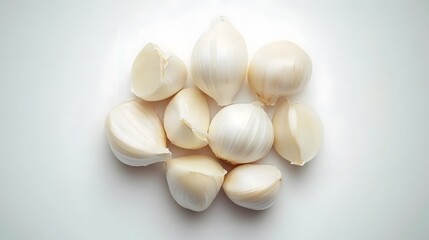 Close-up view of several garlic cloves, some whole and some separated, arranged on a white background.  The garlic appears fresh and is softly lit.