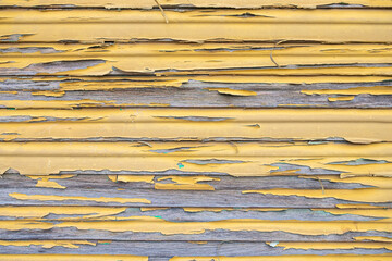 rustic yellow wood with layers of peeling paint, textured wooden fence close up