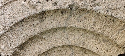 Closeup of ancient stone archway detail showing textured surface and carved curves architecture history building design