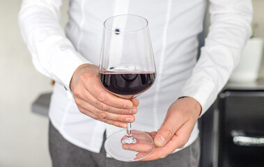 Glass of red wine in hands. Selective focus.