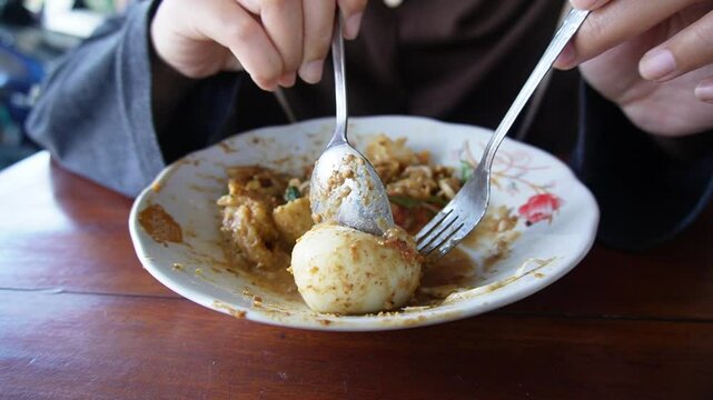 Close up of female hand splitting boiled eggs in a traditional Indonesian food dish, gado gado or lotek