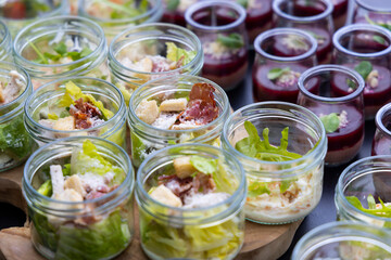 Catering service preparing fresh caesar salad in glass jars for event