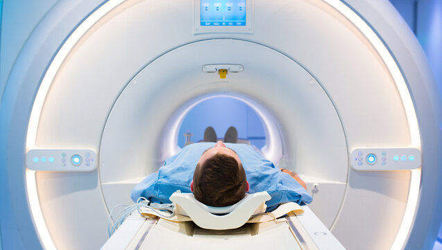 patient undergoing examination using advanced medical technology MRI, CT or PET scan with healthcare worker performing examination procedure