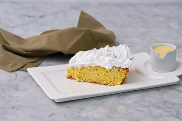 Tres Leches cake Slice with small bowl of extra milk sauce served in tray topped with fluffy...