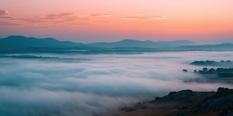 Fototapeta premium A breathtaking landscape featuring misty hills at dawn, where soft colors blend beautifully, inviting feelings of peace and tranquility in nature at sunrise.